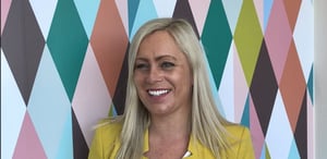 Jane Hill smiling and standing in front of a patterned background